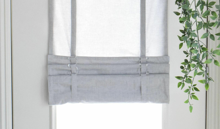 With a tiered tumble shade in New Jersey, you can block sun glare all year round. Gray rolled tumble shade on a glass door